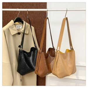 Detailed view of woven tote bags in black brown and khaki hanging on a studio rack