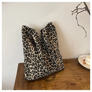 Detail of leopard print canvas tote bag with woven texture on a wooden surface