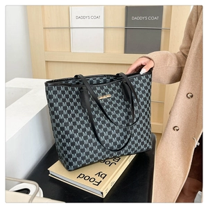 Close-up of black and grey monogram tote bag with gold metal logo and leather straps