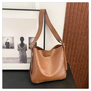 Close-up of brown woven leather texture and golden metal buckle on a large bucket bag