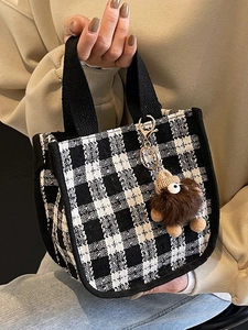 Classic black and white checkered mini handbag with a brown plush monster pendant on strap