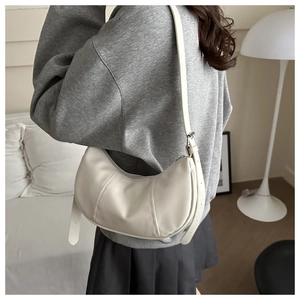 Close-up of white crescent shoulder bag with detailed stitching and adjustable PU strap