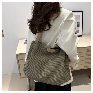 Detail of large woven tote bag with brown leather straps and subtle textured pattern
