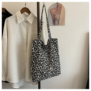 Detail view of large leopard print tote bag styled with a white shirt on a hanger