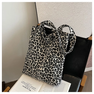 Detail of leopard print canvas tote bag with thick shoulder strap on a black chair