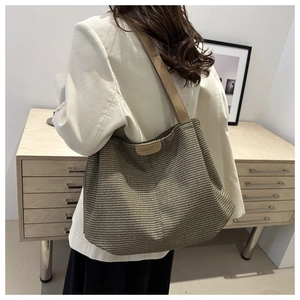 Detailed view of woven hobo tote bag with brown leather strap worn on shoulder