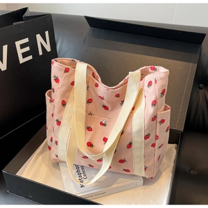 Pink corduroy strawberry tote bag with off-white handles and side pocket in a gift box