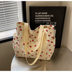 Detail of corduroy tote bag with red strawberry pattern, front pocket and metal buckle