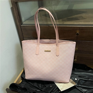 Light pink tote bag with textured monogram print and golden logo on black leather surface