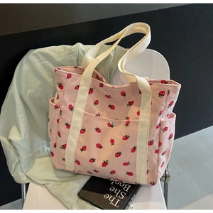 Detailed texture of pink corduroy tote bag featuring red strawberry prints and side pockets