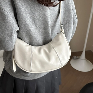 Chic cream semi-circle hobo bag with vertical stitching shown on model's shoulder