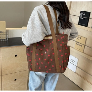 Brown corduroy tote bag with strawberry pattern shown on model for size and fit