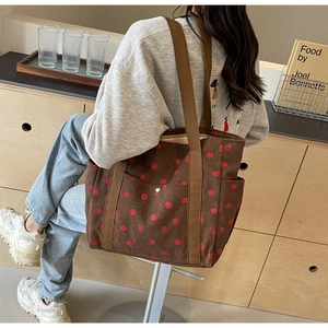 Detail of strawberry print corduroy tote bag showing thick texture and shoulder strap