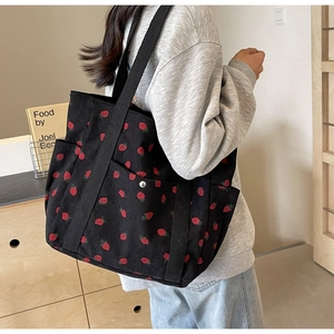 Detail of black corduroy tote bag with strawberry pattern and textured fabric surface