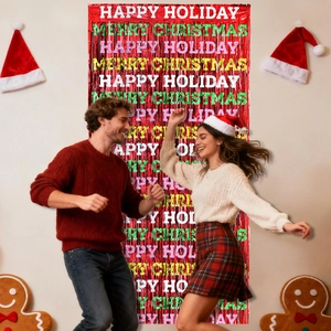 Couple dancing in front of a red Merry Christmas tinsel curtain backdrop with festive print