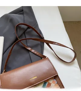 Detailed shot of brown leather bag with knit patchwork texture and gold logo