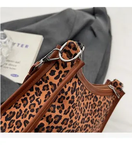 Dettaglio della borsa leopardata con finiture in pelle marrone e dettagli in metallo argento