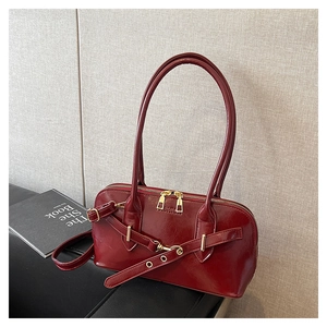Close-up of glossy red rectangular handbag featuring gold hardware and Fashion engraving