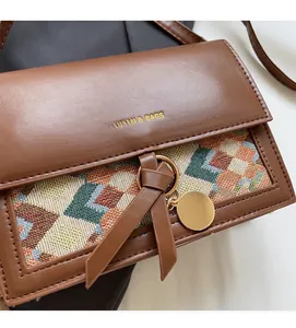 Detail of crossbody bag with colorful woven pattern, gold ring, and leather knot decor