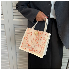Detail of floral lace tote bag featuring red flower patterns and vintage wooden button