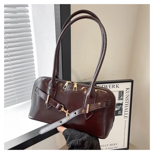 Detailed view of deep brown patent shell bag with golden buckles and fashion logo