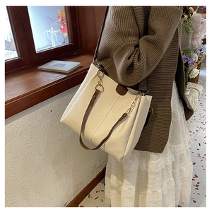 Close-up of cream PU leather tote bag with dual straps and elegant gold chain hardware