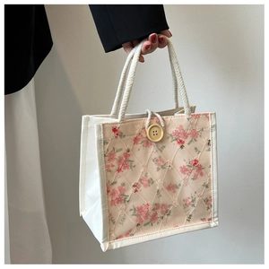 Detail of floral mesh embroidery tote bag with cream rope handle and large wooden button