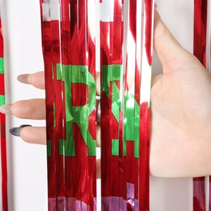 Detail of red metallic fringe curtain with green Merry Christmas foil print texture