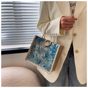 Detail of linen handbag with retro floral embroidery and wooden button closure