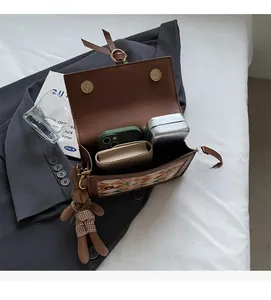 Brown leather crossbody bag with woven pattern and plush bunny charm showing internal space