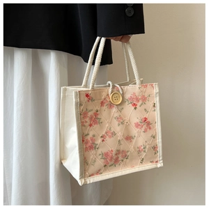 Detail of floral lace tote bag featuring woven handles and a button closure for women