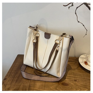 Detail of cream PU leather tote bag featuring gold ring hardware and vintage woven strap