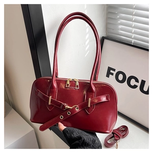 Detail of dark red patent leather shell bag with gold hardware and fashion embossing