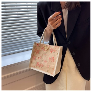 Floral quilted lunch bag with beige button closure and woven rope handles close-up view
