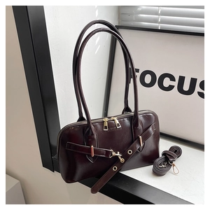 Detailed macro view of the glossy wine red leather shell bag with gold zippers