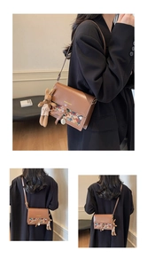 Close-up of vintage brown crossbody bag with colorful woven pattern and rabbit charm