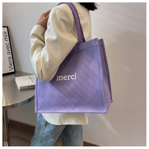 Dettaglio della borsa tote in tela viola con stampa merci bianca portata sulla spalla