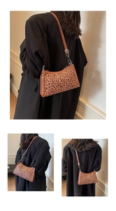 Dettaglio borsa a tracolla leopardata con cinturino marrone su un blazer nero