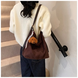 Détail d'un grand sac cabas marron foncé avec pendentif ours en peluche et foulard en soie