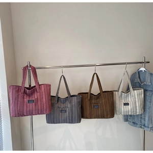 Série de cabas en toile rayée en quatre couleurs suspendus à un support métallique