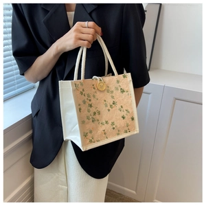 Detail of white canvas lunch bag with beige lace and green floral embroidery
