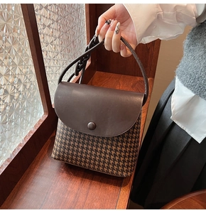 Detail view of brown leather and houndstooth bucket bag with vintage chain decoration
