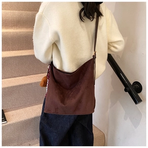 Détail du grand sac hobo en daim marron avec bandoulière et pendentif en boule de fourrure