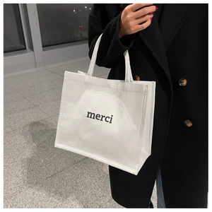 Dettaglio della borsa tote in tela bianca con stampa 'merci' nera e manici resistenti