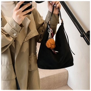 Detail of a large black hobo tote bag with a cute brown teddy dog pendant on model