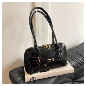 Detail of black patent leather shell bag with gold zipper and embossed fashion logo