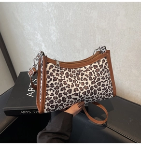 Dettaglio borsa leopardata con finiture in pelle marrone e cerniera metallica argentata