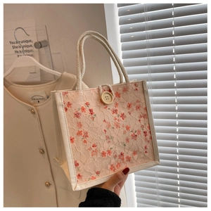 Detailed shot of pink floral lace tote bag with woven rope handles and wooden button accent