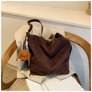 Détail d'un cabas en daim marron foncé avec charme chien en peluche sur un blazer