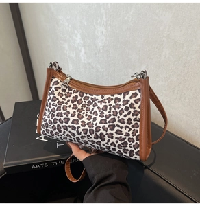 Dettaglio borsa leopardata con finiture in pelle marrone e chiusura lampo superiore